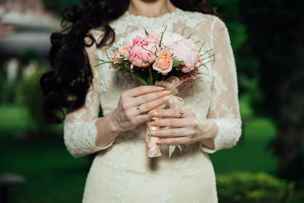 Mobile makeup artist Sydney: bride in a lace long-sleeve gown holding a soft pink and white bouquet