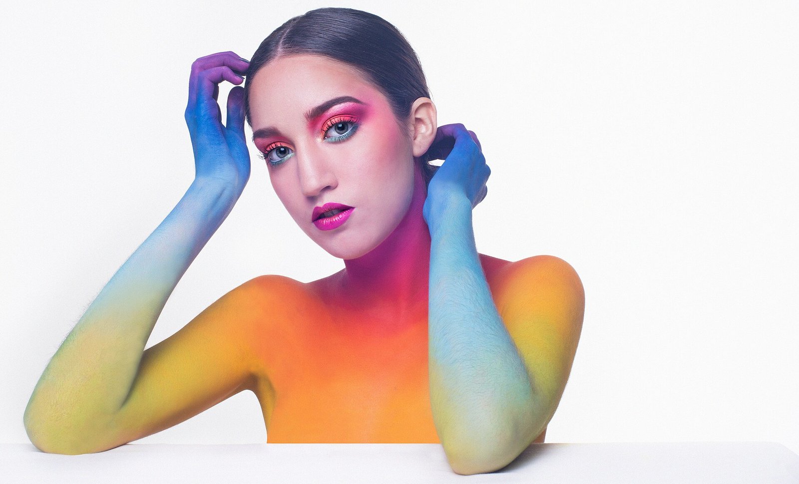Commercial hair & makeup artist Sydney: colour-blocked body paint beauty shoot in rainbow tones against a white backdrop