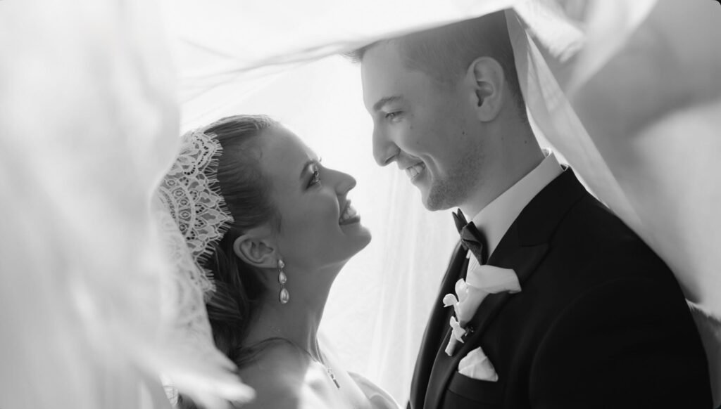 Bridal hair & makeup artist Sydney: black and white portrait of a bride and groom facing each other beneath her veil